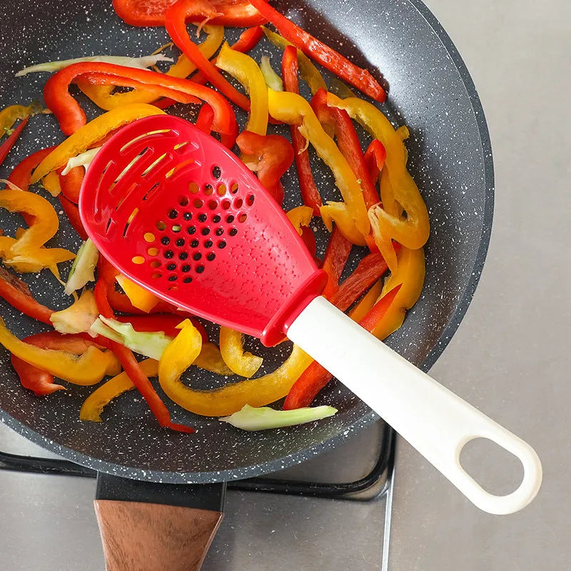 Multifunctional slotted cooking spoon in red plastic with serrated edge and half-enclosed head for scooping rice