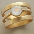 Gold-plated titanium steel ring with a hollow geometric design and micro-inlaid white chalcedony detail.