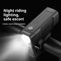 Black bicycle headlight with LED lens mounted on handlebars via a quick-release strap bracket.