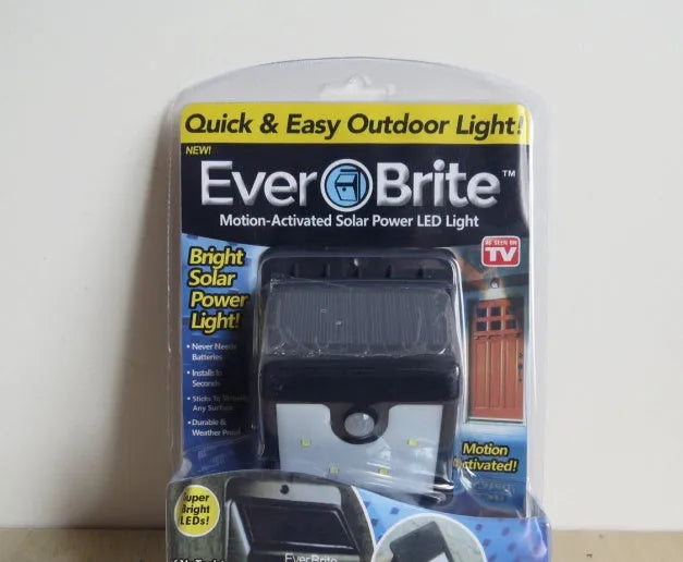 Grey outdoor solar security light with four LED bulbs and a motion sensor mounted on a wall
