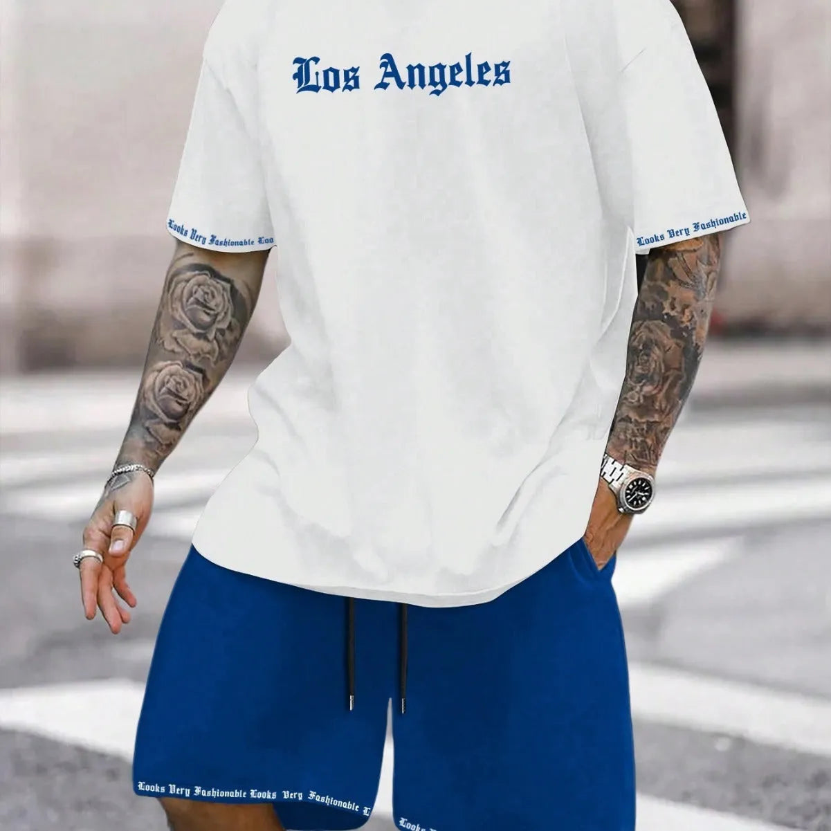 Man wearing a blue printed short-sleeved top and matching shorts from a sports-style two-piece set.