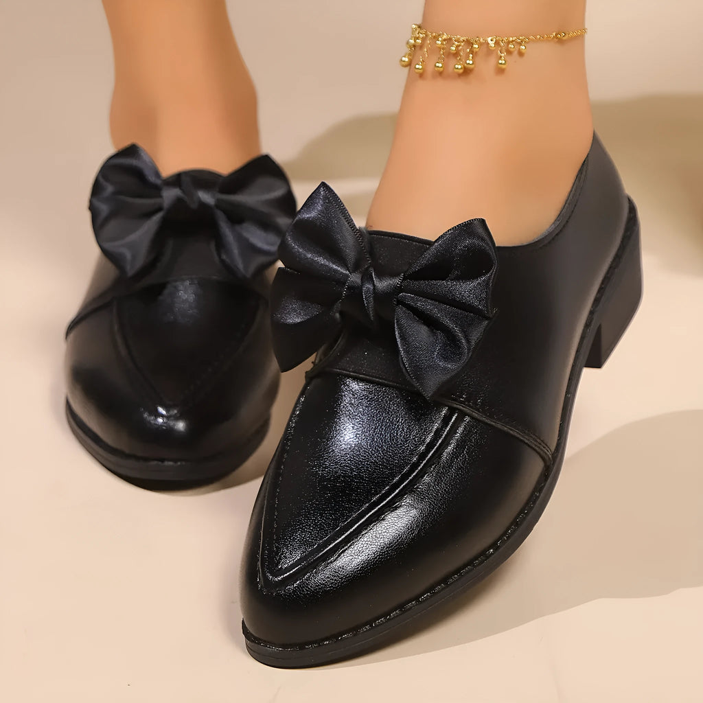 Women's leather-look slip-on shoes with decorative bow buckle detail and pointed toe