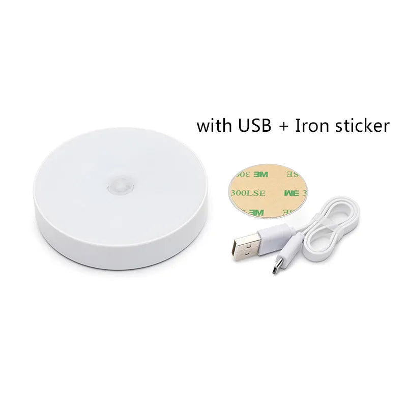Small round white LED night light with motion sensor, shown with USB charging cable and adhesive tape.