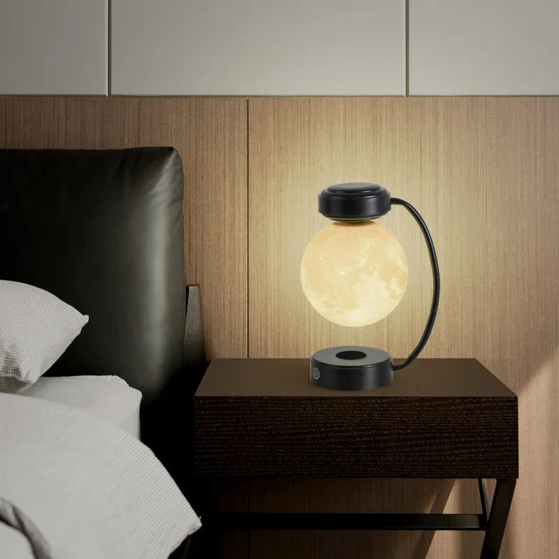 Magnetic levitation moon lamp with 3-colour light changing effect, black elbow base, on a bedside table