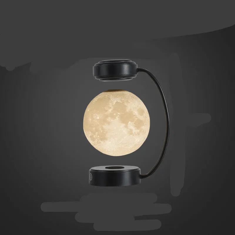 Magnetic levitation moon lamp with 3-colour light changing effect, black elbow base, on a bedside table