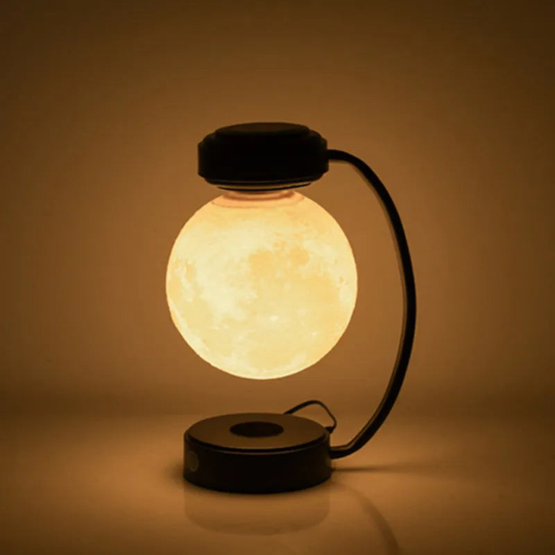 Magnetic levitation moon lamp with 3-colour light changing effect, black elbow base, on a bedside table
