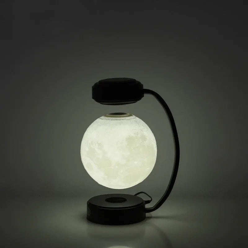 Magnetic levitation moon lamp with 3-colour light changing effect, black elbow base, on a bedside table