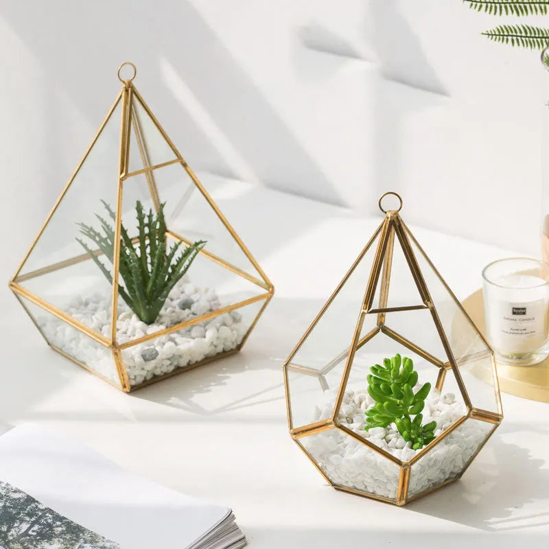 Metal and glass succulent pot decoration in golden love style on a wooden shelf