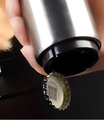Automatic stainless steel beer bottle opener with magnetic cap catch on a table