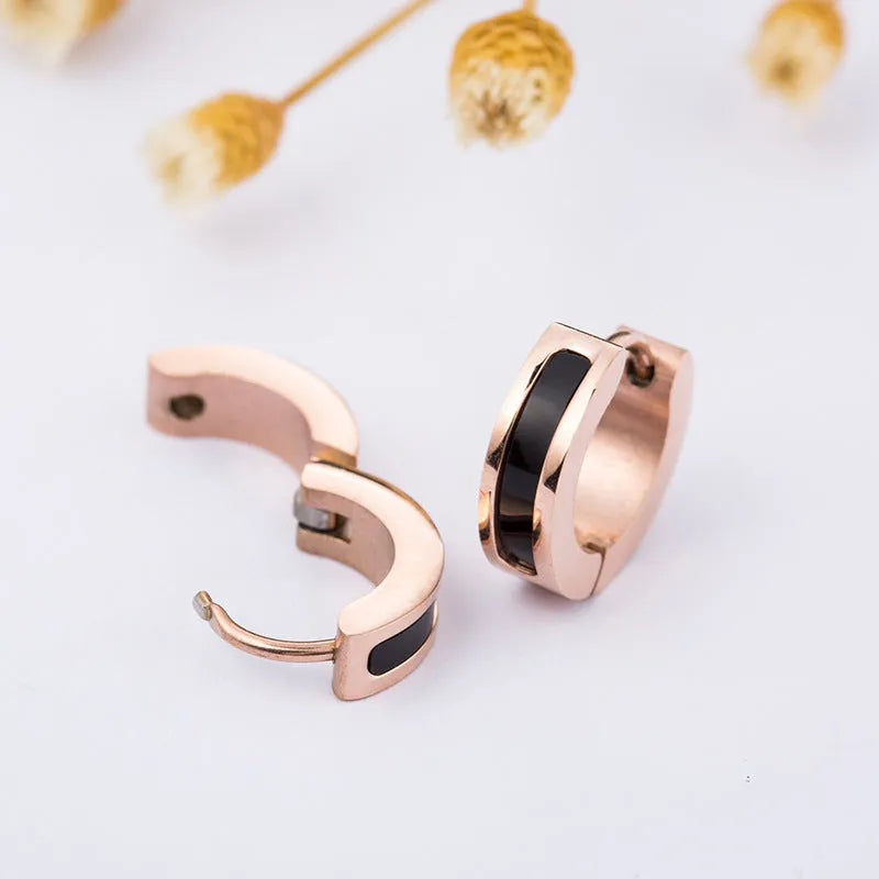 Pair of black titanium steel earrings with geometric shell inlay on white background