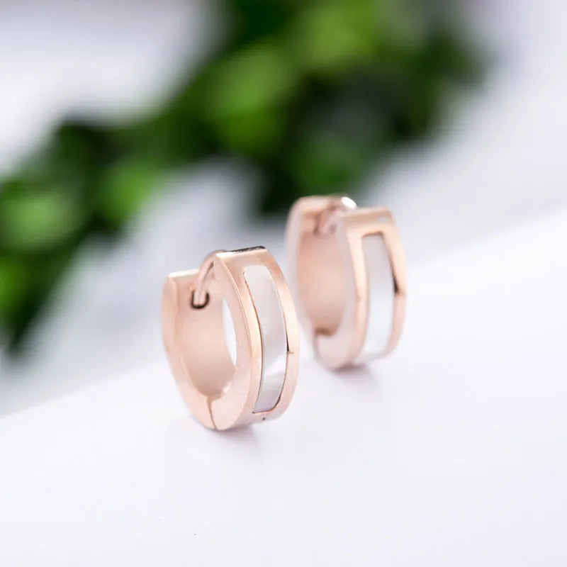 Pair of black titanium steel earrings with geometric shell inlay on white background