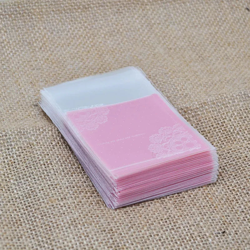 Pink self-adhesive plastic packaging bag with clear window and resealable strip, shown flat and filled.