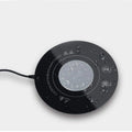 Black USB-powered hot and cold drink coaster with tempered glass top on a wooden desk.