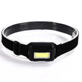 Compact black COB LED headlight with adjustable polyester headband on a dark background.