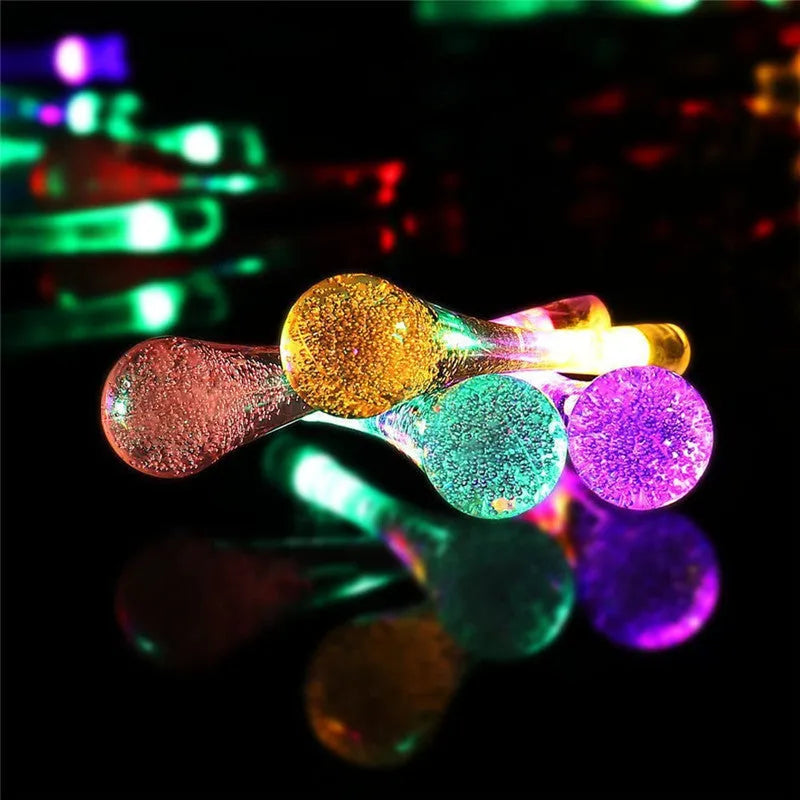6.5 metre long solar-powered LED garden string lights with white bubble drop shaped lamps on a green lawn