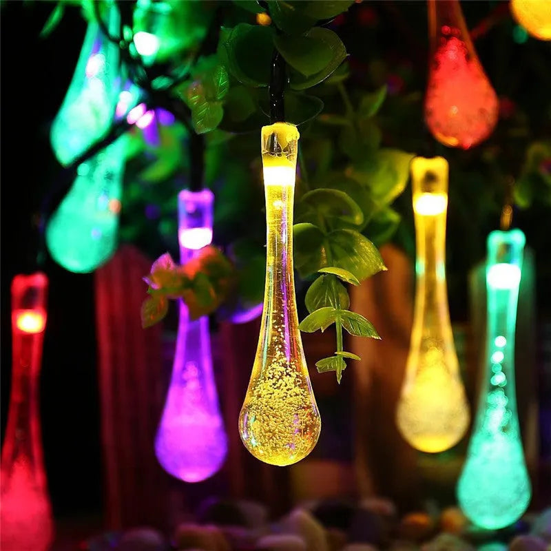6.5 metre long solar-powered LED garden string lights with white bubble drop shaped lamps on a green lawn