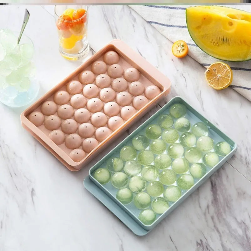 Round ball ice cube tray in sky blue with 33 grids, empty and filled with water, on a kitchen countertop
