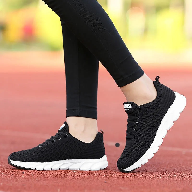 Women's running shoes in black, pink, or white with a fly weave upper and durable sole.