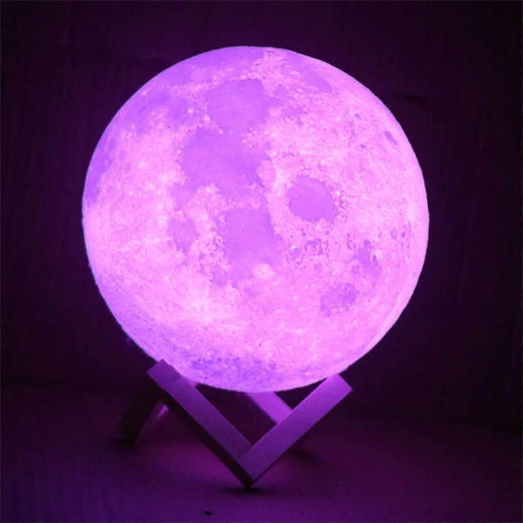 3D printed white moon lamp with detailed craters on a wooden stand, glowing with warm yellow light.