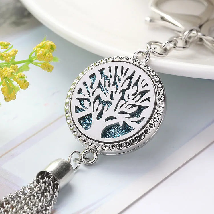 Silver alloy tassel aromatherapy car pendant with long chain on a coloured background.