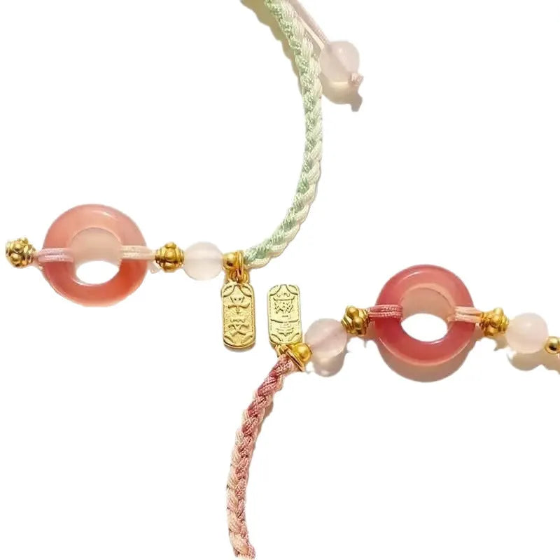 DIY woven watch band with peace buckle in peach blossom green, pink, and black colours on a unisex hand strap