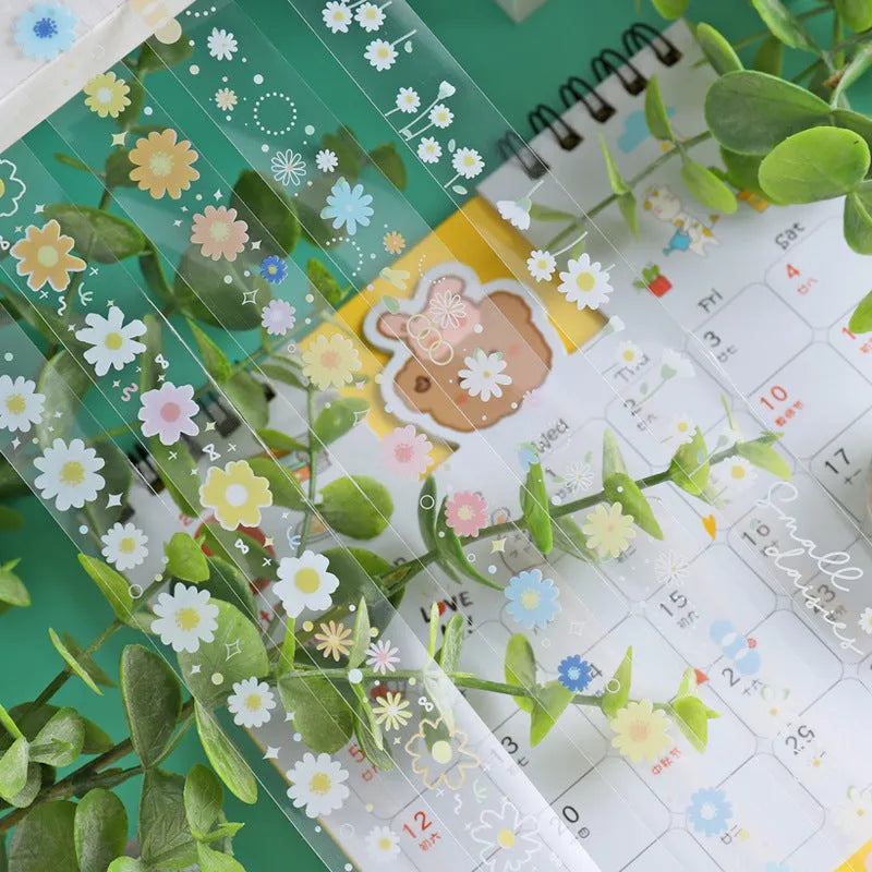 Five rolls of transparent adhesive tape with yellow and white daisy cartoon pattern on a clear background.