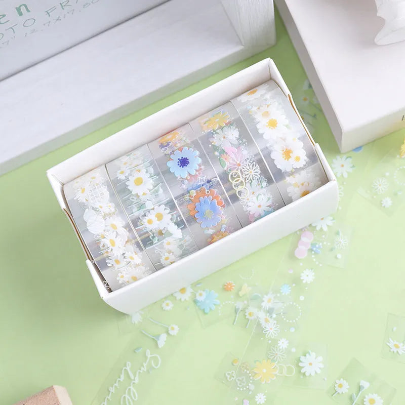 Five rolls of transparent adhesive tape with yellow and white daisy cartoon pattern on a clear background.