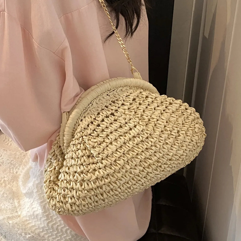 Women's beige straw shoulder bag with chain detail and a zippered interior.