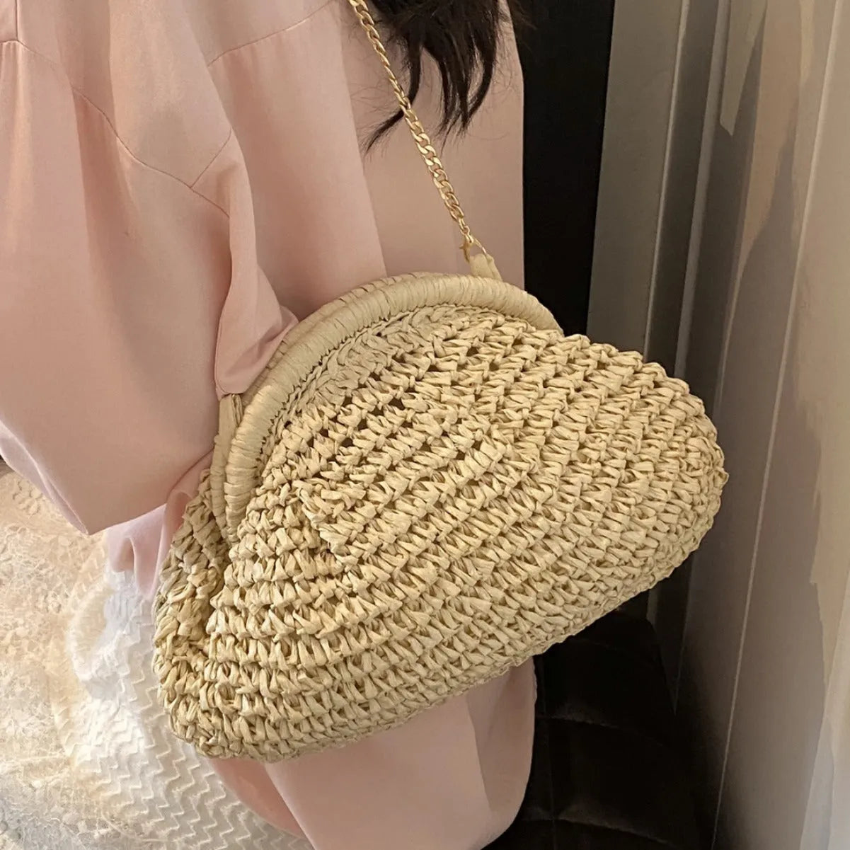 Women's beige straw shoulder bag with chain detail and a zippered interior.