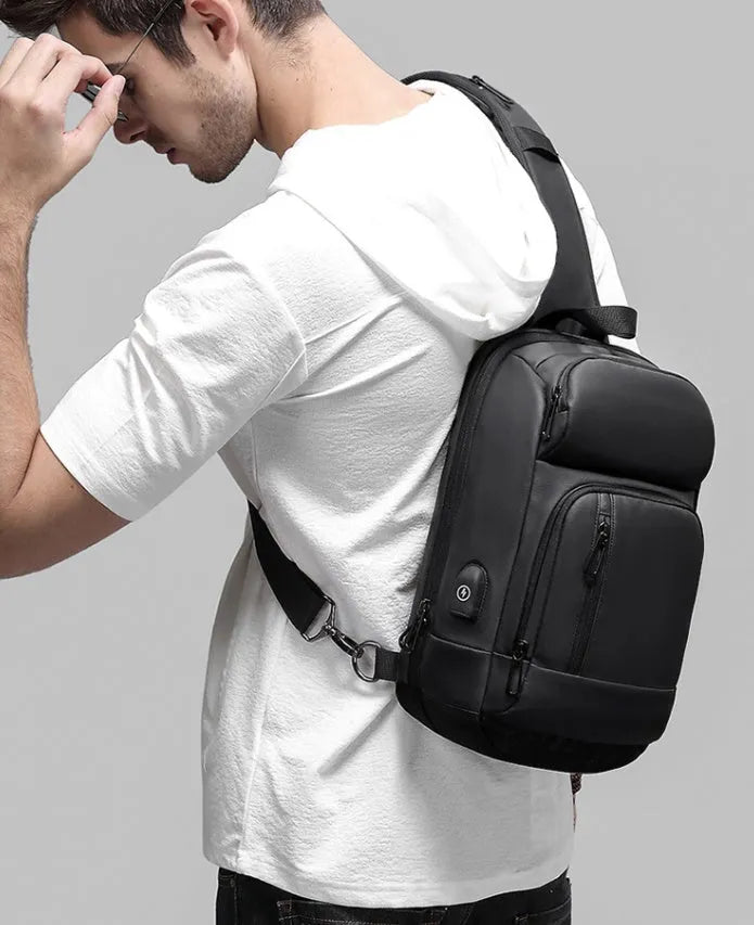 Black PVC outdoor shoulder bag showing computer pocket, air cushion strap, and square vertical design
