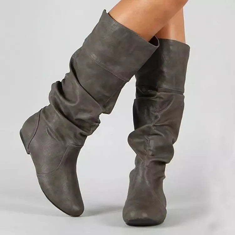 Women's flat heel slip-on boots in black with a round toe and high calf shaft, made from artificial PU with a rubber sole.