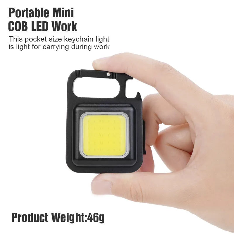 Black aluminium alloy COB keychain flashlight on a metal surface, magnetic base attached, 6x4.2cm size, with foldable handle extended