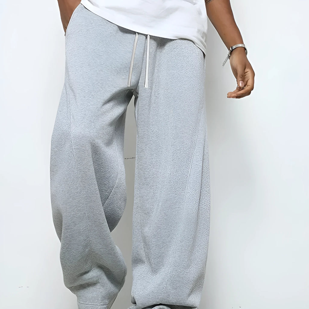 Man wearing solid grey straight-leg casual trousers with an elasticated waistband.