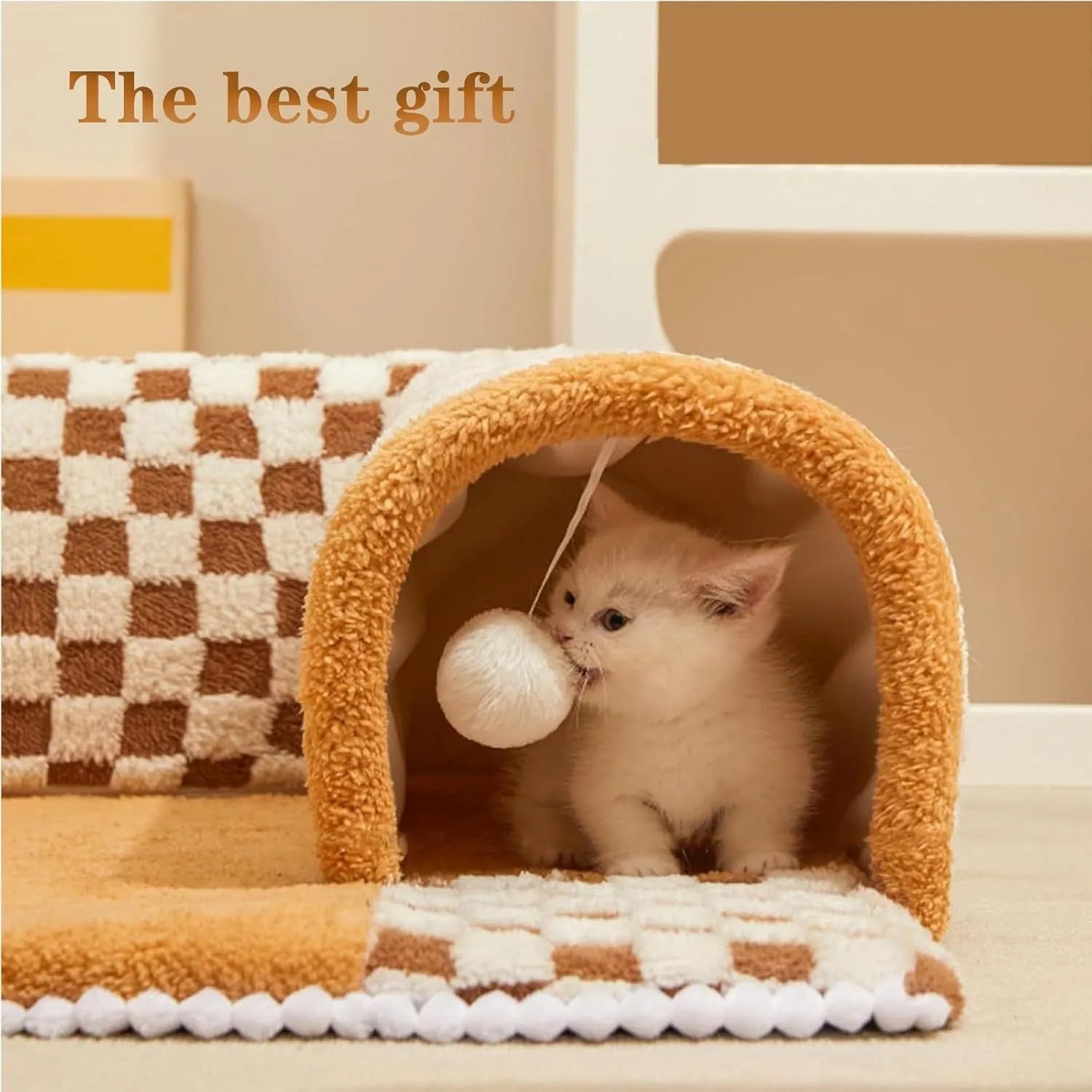Brown plaid plush cat tunnel bed with a central mat on a wooden floor.