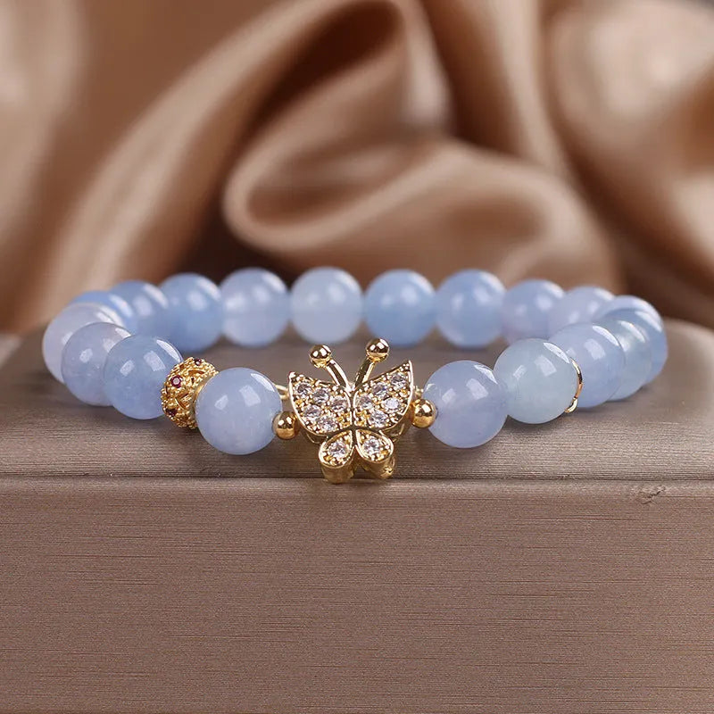 Sky blue crystal butterfly stretch bracelet for women with pearl and rhinestone accents on a plain background