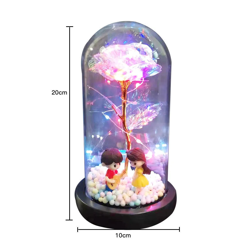 Gold artificial rose inside glass dome with LED lights on black base for home display