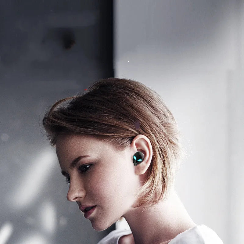 Creative Outer T8 Starman black and white alien design wireless earbuds with LED lights next to charging case.
