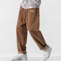 Men's loose straight corduroy sports trousers in black, front view, lying flat, showing waist and leg cut