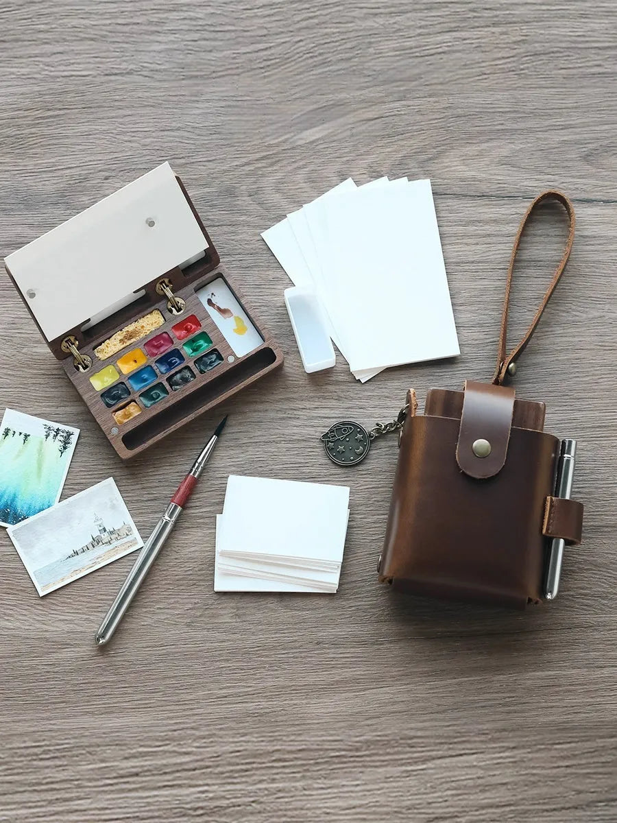 Mini wooden watercolour paint box open to show compartments filled with professional artist pigments.