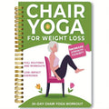Green coil-bound 30-day chair yoga training guide notebook with calendar layout on a desk