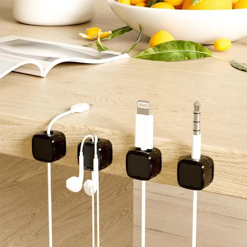 Magnetic cable clip in white holding a USB cable under a desk, with adhesive backing visible