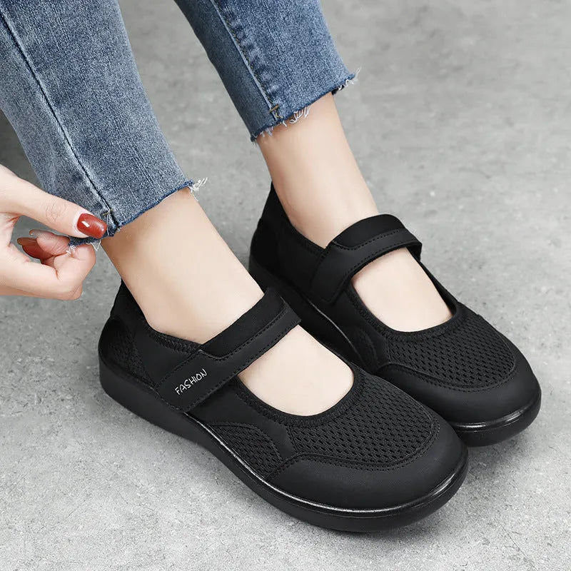 Women's grey low-top cloth shoes with mesh upper and Velcro strap on a flat sole.
