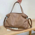 Large soft surface PU messenger bag in horizontal square shape with shoulder strap and top handle.