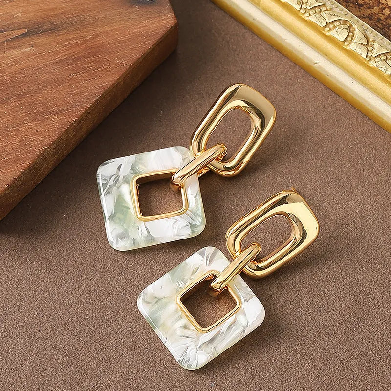 Dignified hollow geometric square copper earrings with electroplated finish on white background