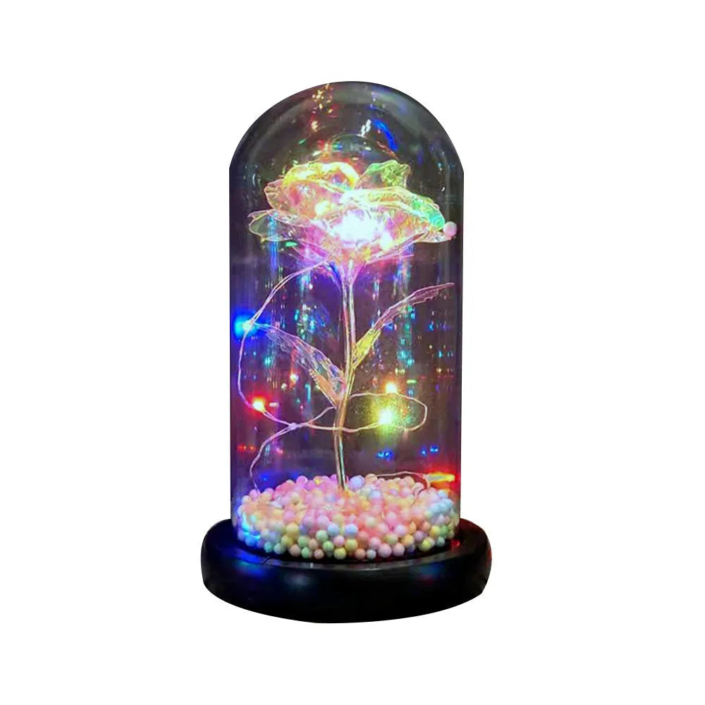Gold artificial rose inside glass dome with LED lights on black base for home display