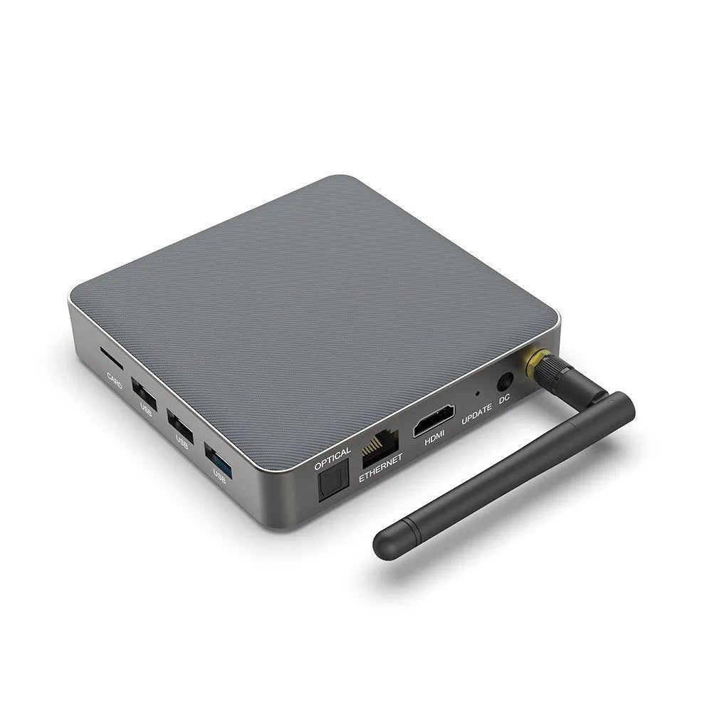 Square black Android TV set-top box with HDMI port and remote control on a wooden surface