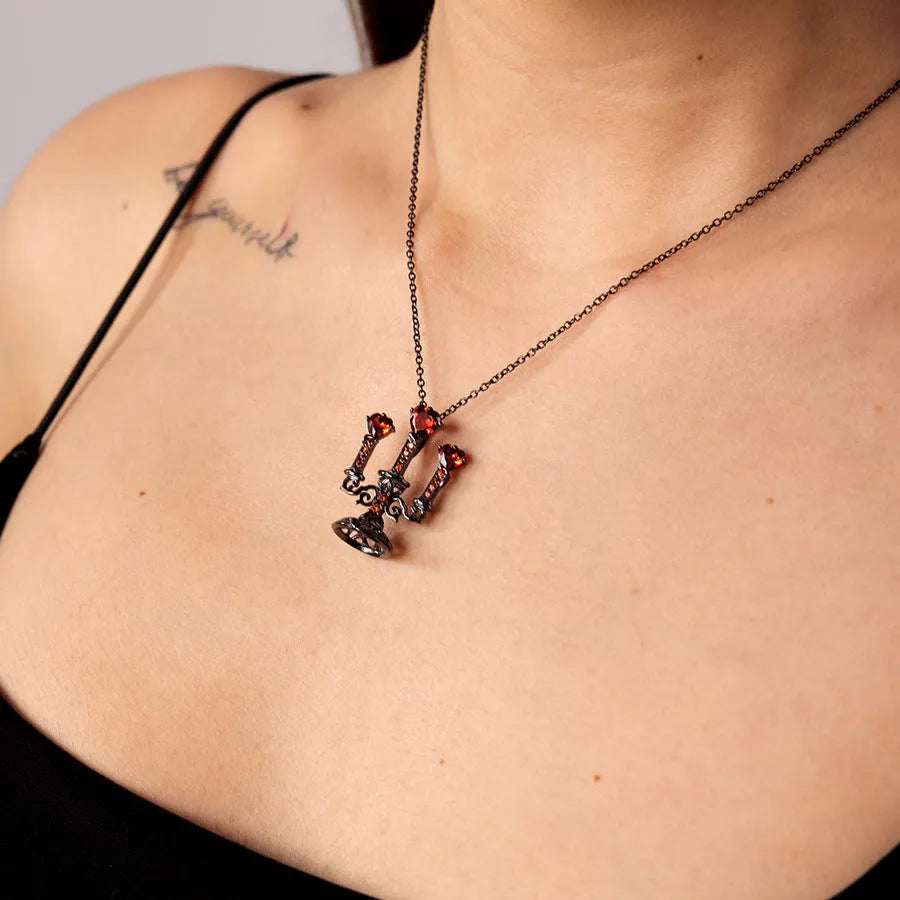 Close-up of a women's Gothic alloy necklace with a hollow candlestick pendant and cross chain links.