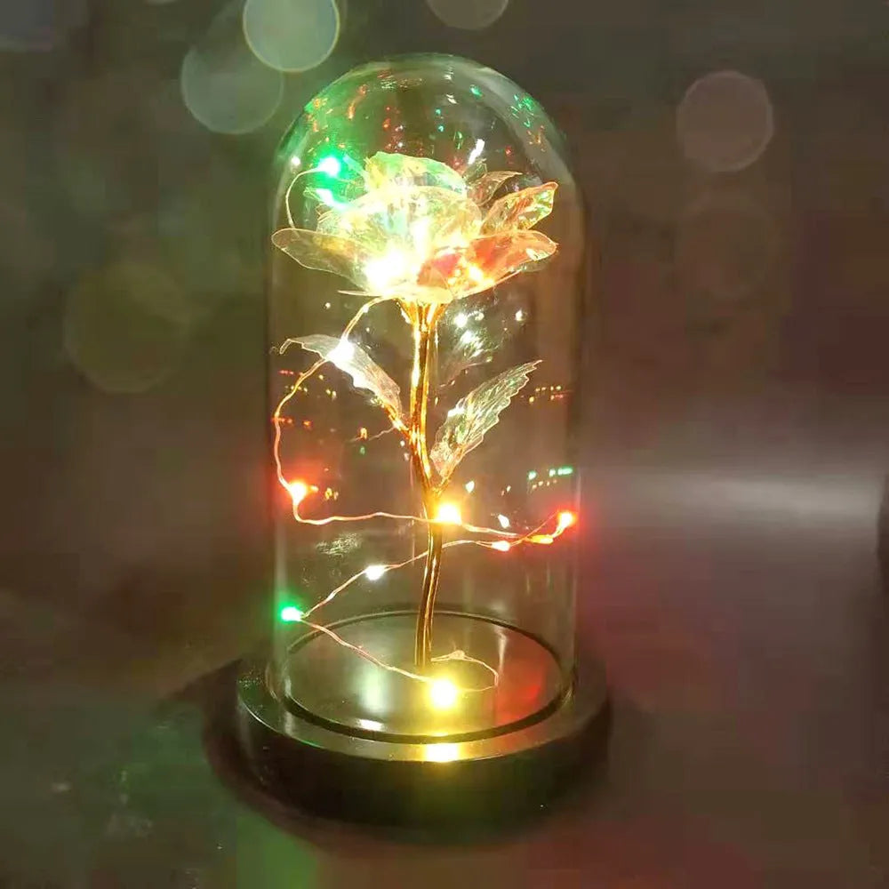Gold artificial rose inside glass dome with LED lights on black base for home display