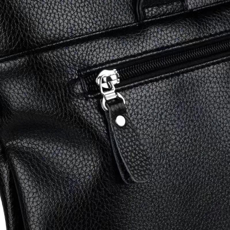 Men's black PU leather crossbody messenger bag with splicing design, shown next to a tablet for scale.