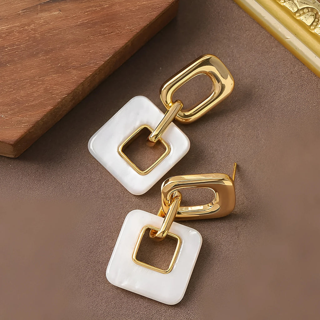 Dignified hollow geometric square copper earrings with electroplated finish on white background